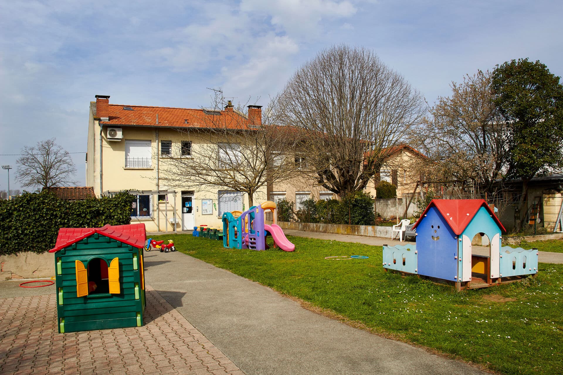 Le jardin ensoleillé de la crèche Petit à Petit, avec ses cabanes et jeux colorés